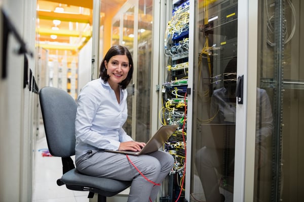 Portrait of technician working on laptop in server room