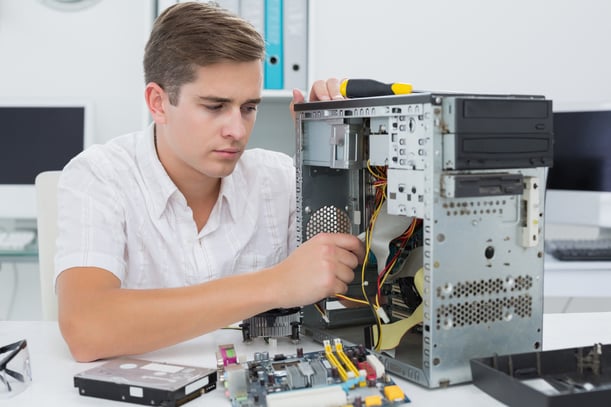 Young technician working on broken computer in his office